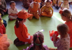 Dzieci słuchające zagadki na dywanie.